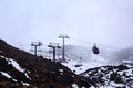 Cable cars and ski lifts going up and down snow blanketed slopes of the mountain while a snow storm building up. Mt