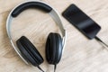 Modern headphones connected to music player on wooden table Royalty Free Stock Photo