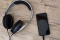 Modern headphones connected to music player on wooden table Royalty Free Stock Photo