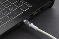 Cable with modern connector USB Type C for charging and syncing your laptop with gadgets. White cable plugged in laptop. Royalty Free Stock Photo