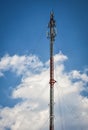 Cellular transmission tower with white clouds and blue sky background. Royalty Free Stock Photo