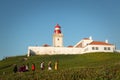Cabo da Roca, Portugal - March, 2019: white lighthouse on cliffs with green grass at evening time.