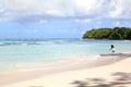 White sand lonely beach, blue sea, green palm trees, island background and a little girl touches the water in the sea Royalty Free Stock Photo