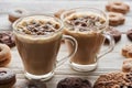 Cacao with marshmallow in cups near cookies on white wooden table.