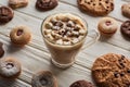 Cacao with marshmallow in mug near cookies on white wooden table.