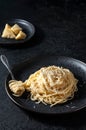 Cacio e Pepe - Italian Pasta with Cheese and Pepper on Black Plate on Dark Background