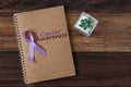 Cactus, lavender ribbon and book with CANCER AWARENESS text on wooden background Royalty Free Stock Photo