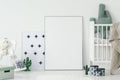 Cactus pillow in white cradle next to empty poster with mockup i