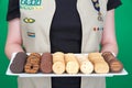 Cadette Girl Scout holding plate of Girl Scout cookies on green background