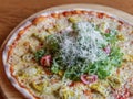 Caesar pizza on a wooden board with chicken and a slide of Caesar salad in the center, closeup