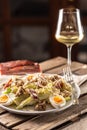 Caesar salad with boiled eggs, bacon, and croutons served on a plate next to a glass of white wine Royalty Free Stock Photo