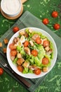 Caesar salad with chicken fillet, tomatoes, croutons and parmesan in a plate on a rustic wooden background Royalty Free Stock Photo