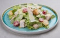 Caesar salad with chicken, Parmesan and cherry tomatoes. In a blue plate on a textile background