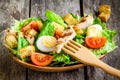 Caesar salad with croutons, quail eggs, cherry tomatoes and grilled chicken in wooden plate Royalty Free Stock Photo