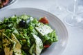 Caesar salad of herbs, cheese and olives on a white plate Royalty Free Stock Photo