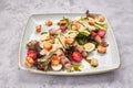 Caesar salad with herbs chicken bacon eggs and tomatoes on a square light plate, on a light background Royalty Free Stock Photo