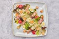 Caesar salad with herbs chicken bacon eggs and tomatoes on a square light plate, on a light background Royalty Free Stock Photo