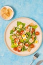Caesar salad with romaine lettuce, cherry tomatoes, boiled quail eggs and croutons on a light ceramic plate on a blue concrete Royalty Free Stock Photo