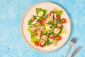 Caesar salad with romaine lettuce, cherry tomatoes, boiled quail eggs and croutons on a light ceramic plate on a blue concrete Royalty Free Stock Photo