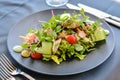Caesar salad with salmon on black dish