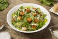 Caesar salad in a white bowl with leaves and a sauce boat and parmesan. Selected focus.