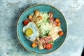 Caesar salad with fried egg. Beautiful serving dishes. Light gray background. Restaurant menu