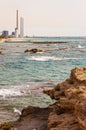 Rocks on the beach, rocky Mediterranean sea coast waters and Orot Rabin, a coal-fired power station Royalty Free Stock Photo