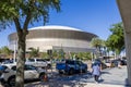 The Caesars Superdome with lush green trees, cars driving on the street and blue sky in New Orleans Louisiana Royalty Free Stock Photo