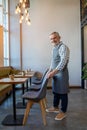 Waiter putting chairs in order in the cafe premises Royalty Free Stock Photo
