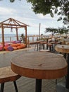 Cafe next to the beach. Tables and bar stools made from sawn wood, a tent with soft, low mattresses, scattered multi-colored Royalty Free Stock Photo