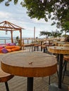 Cafe next to the beach. Tables and bar stools made from sawn wood, a tent with soft, low mattresses, scattered multi-colored Royalty Free Stock Photo