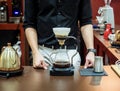 Cafe professional barista brews coffee by an alternative method in pour over, filter on a dark background. Coffee maker and drip k Royalty Free Stock Photo