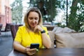 in a cafe at a table, a blonde in a yellow dress looks at the phone