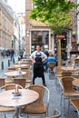 Cafe with tables in the street and a waiter standing near the Manneken Pis monument in Brussels, Belgium