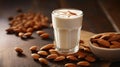 a caffee latte in a glas made with almond milk surounded by brown almonds