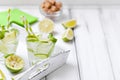 Caipirinha, mojito cocktail with lime, brown sugar, ice and mint leaves in beautiful glasses, cut green citrus on white wooden bac Royalty Free Stock Photo