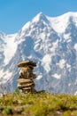 Cairn at mountains summit - stacked rocks ahead of snow mountain peaks