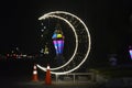 Cairo, Egypt, April 17 2023: A crescent made with led lights with Ramadan Fanous lamp lantern in the street as a festive sign