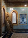 Wooden golden ornate minbar Platform, wooden arched window framed by golden ornate floral pattern, and Turkish ceramic tiles