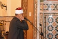 A mosque Imam preacher muezzin in front of the microphone reciting Adhan Azan or calling loudly for the prayer