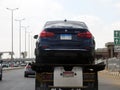 Cairo, Egypt, March 15 2023: A tow recovery transporter hydraulic flatbed truck moving BMW 320i car moving in the street Shinzo Royalty Free Stock Photo