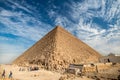 View of the incredibly majestic pyramid of the cheops on a sunny day in the desert with a road Royalty Free Stock Photo