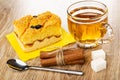 Cake with jam and prune on paper napkin, cup with tea, cinnamon sticks, sugar cubes, spoon on wooden table Royalty Free Stock Photo