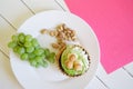 Cake, a bunch of grapes and pistachios in a plate on a white and pink background. Country breakfast Royalty Free Stock Photo