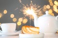 Cake with burning sparkler on table against blurred festive lights Royalty Free Stock Photo