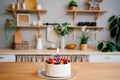Cake with candle number two and fruit on table on Scandinavian-style kitchen Royalty Free Stock Photo