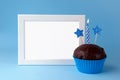 Cake with candle and photo frame on blue background closeup Royalty Free Stock Photo