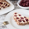 cake with cherries, cream and chocolate on a light wooden background