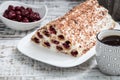 cake with cherries, cream and chocolate on a light wooden background