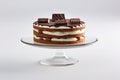 A cake with chocolate and white frosting on a glass cake plate. Generative AI image.